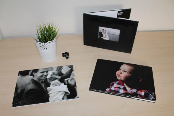  3 fotoalben auf tisch mit blumentopf kind ist zu sehen